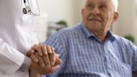 A doctor holding an older patient's hand.